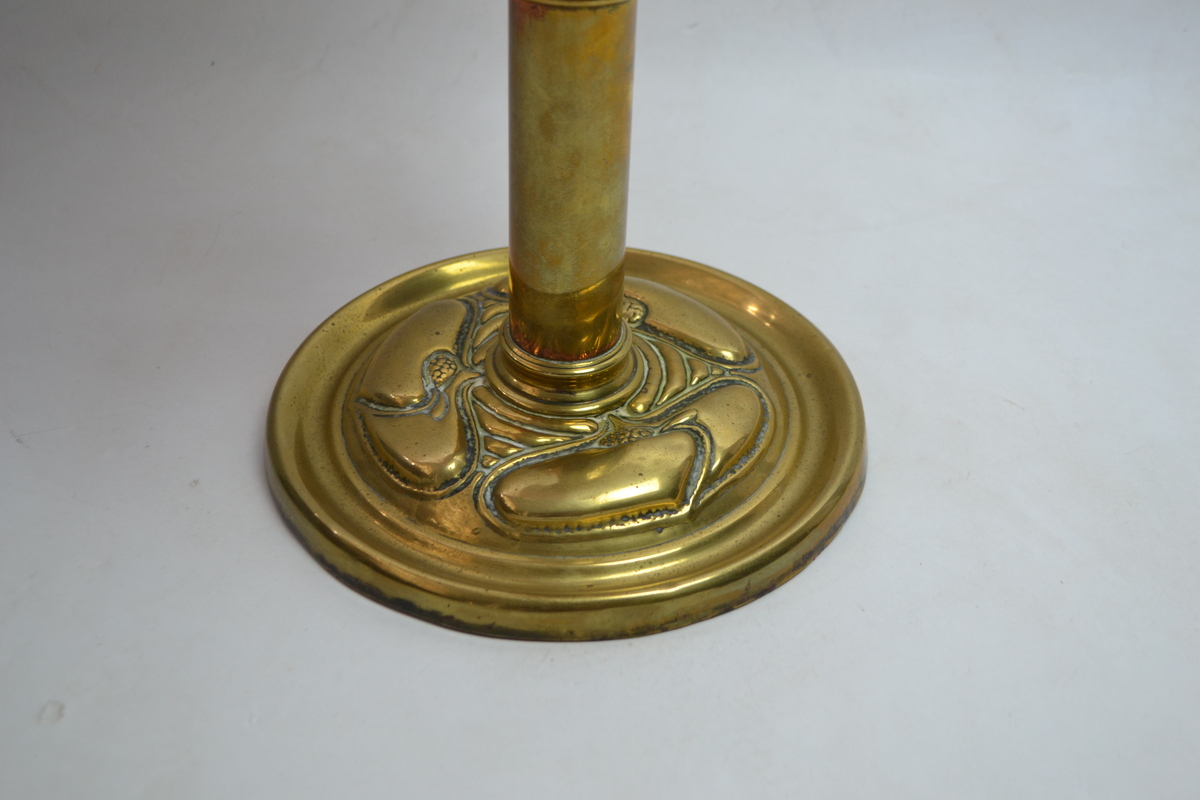 An Art Nouveau Brass Based Oil Lamp With Enamel Painted Cranberry Ceramic reservoir